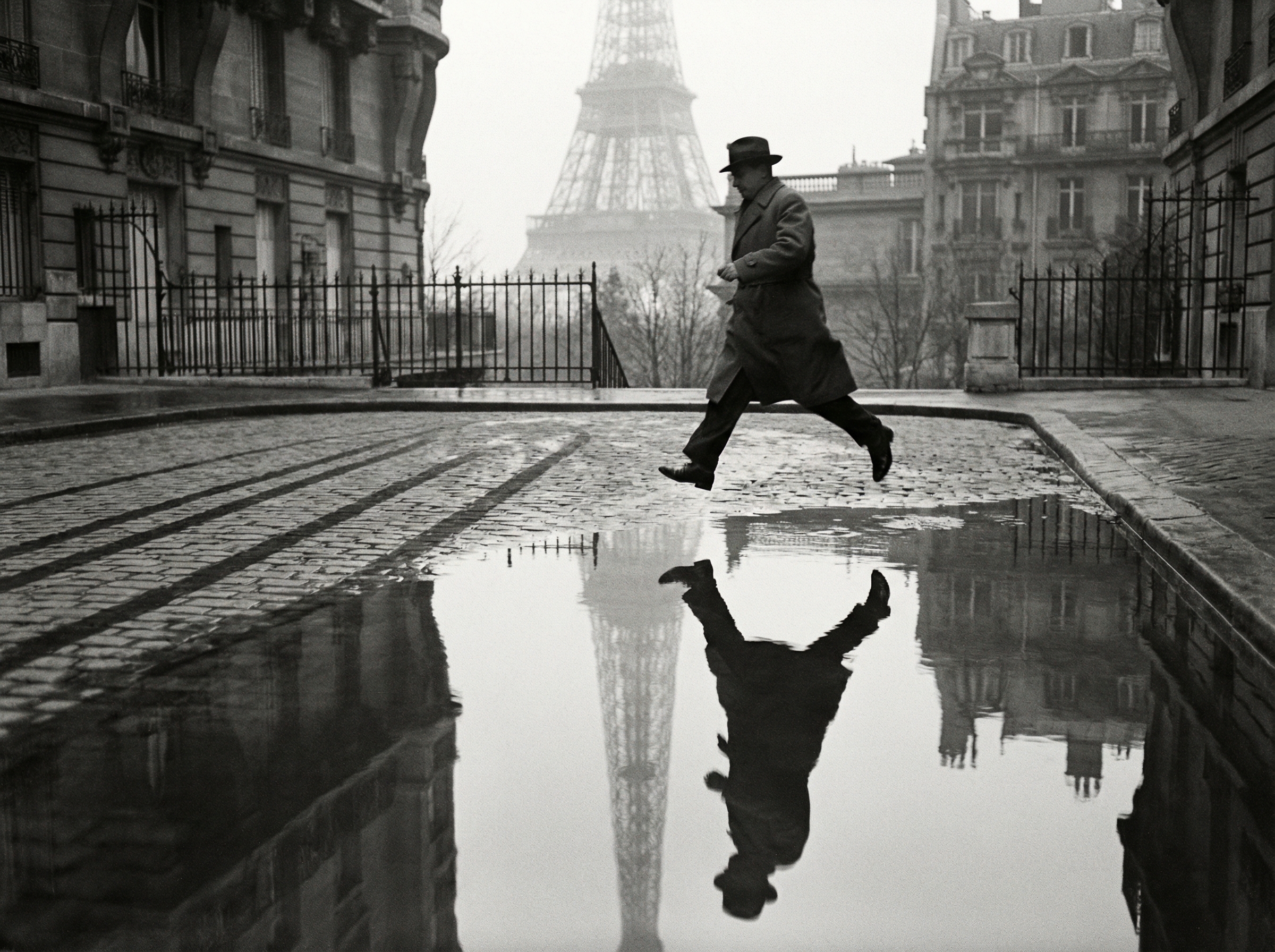 A geometric composition in the style of Cartier-Bresson, with a figure leaping over a puddle