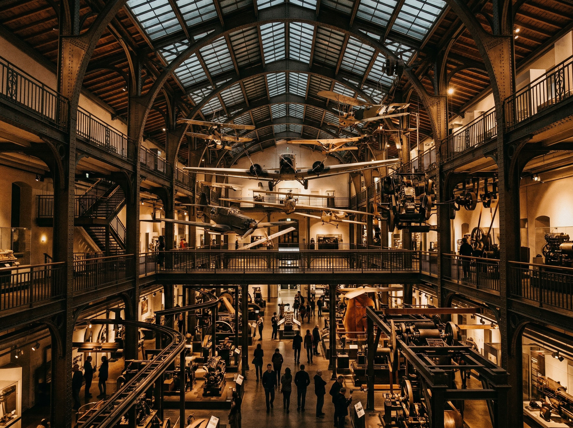 Interior of the Deutsches Museum with vintage aircraft and machinery suspended from high ceilings in dramatic museum lighting