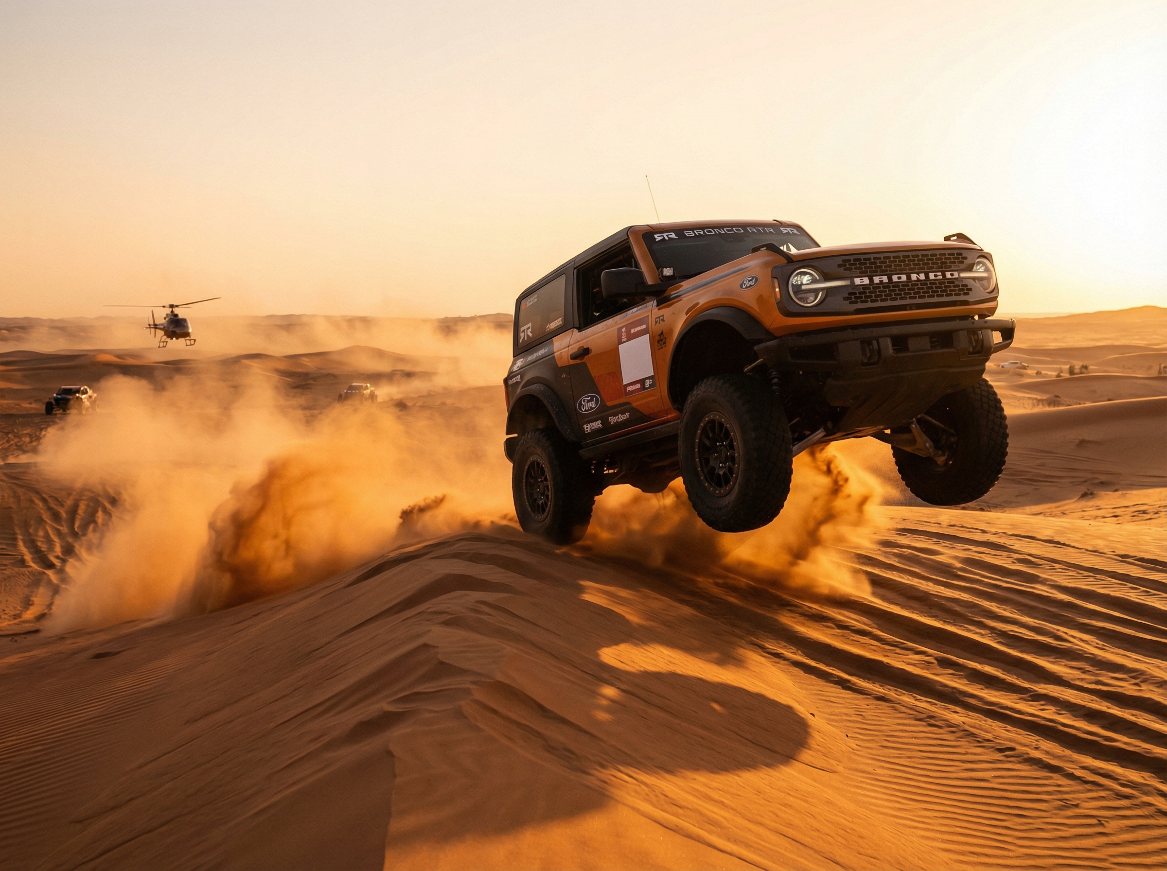 Ford Bronco RTR mid-jump over sand dune with dust cloud