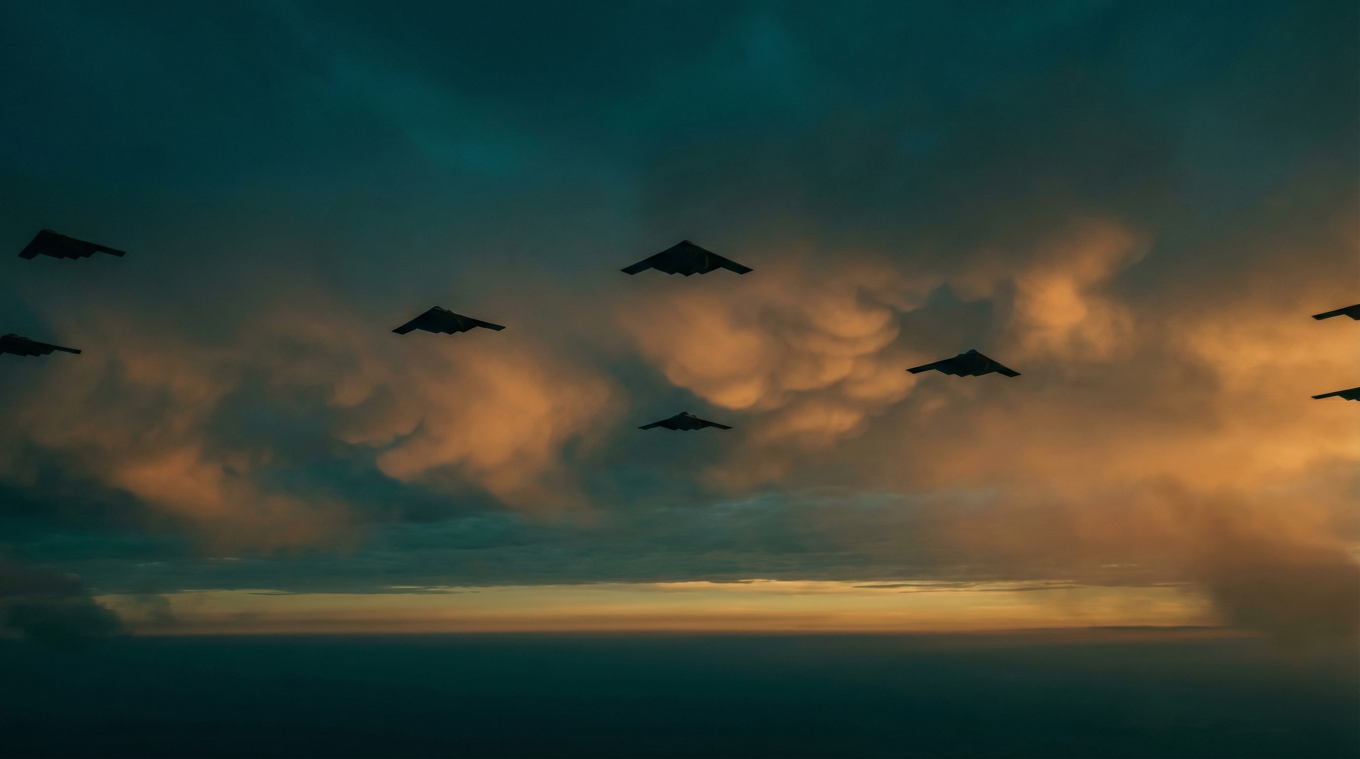 Formation of military drones silhouetted against a dramatic twilight sky