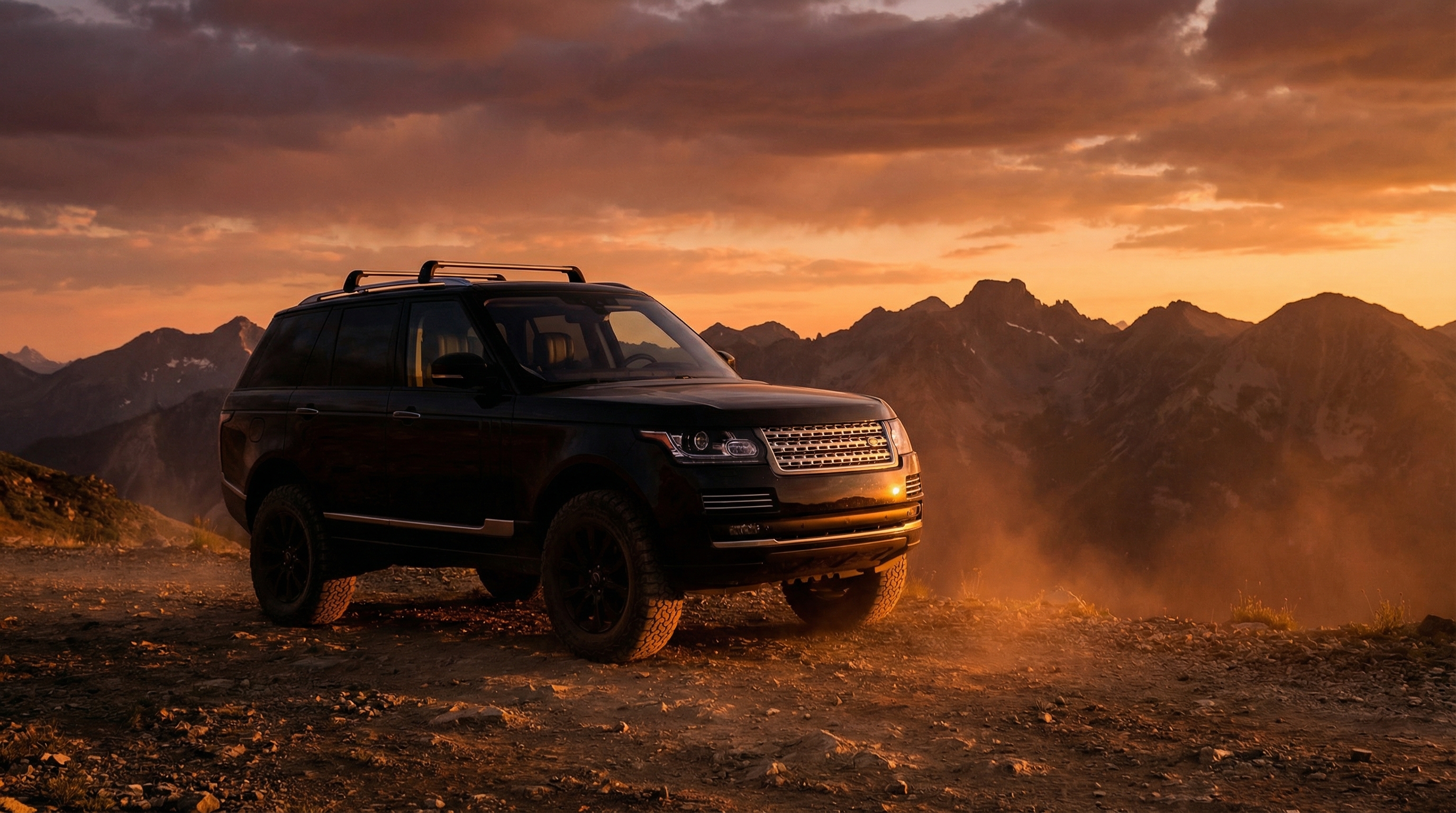 Luxury SUV silhouette against dramatic sunset on mountain trail